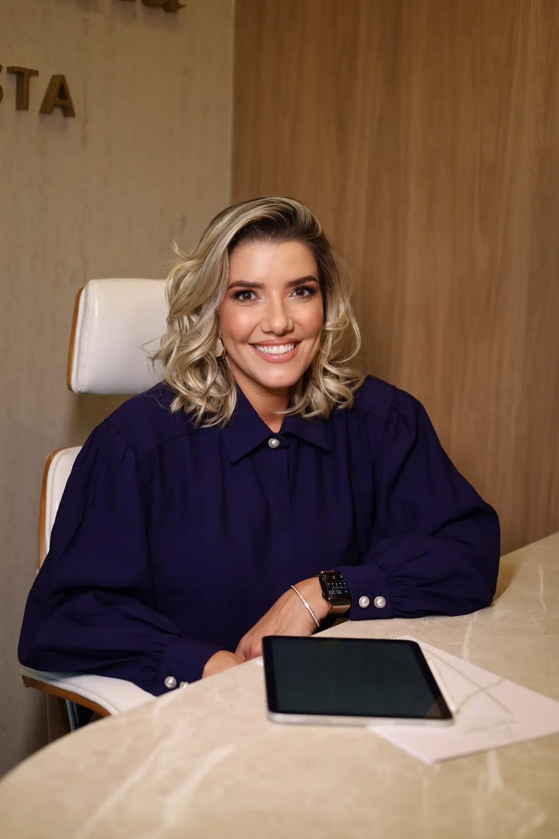 Thayse Villalta sentada à mesa do consultório durante um atendimento